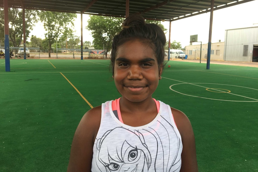 A young girl smiles into the camera.