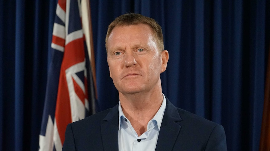 Paul Kirby stands near the Australian flag