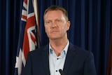 Paul Kirby stands near the Australian flag