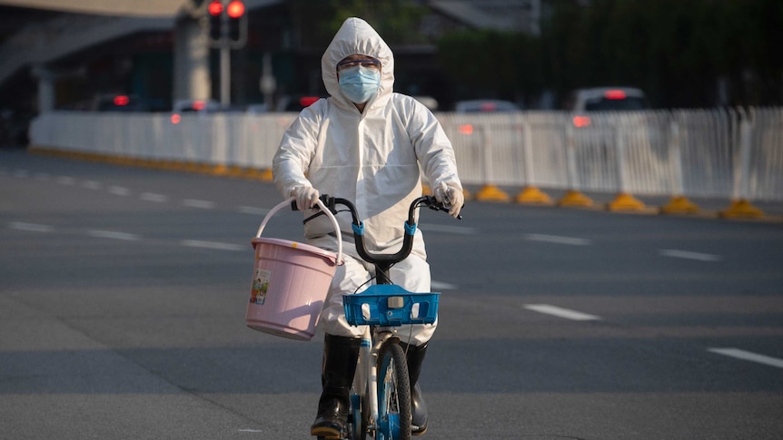 A resident wearing mask and suit against the coronavirus cycles in Wuhan.