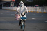 A resident wearing mask and suit against the coronavirus cycles in Wuhan.