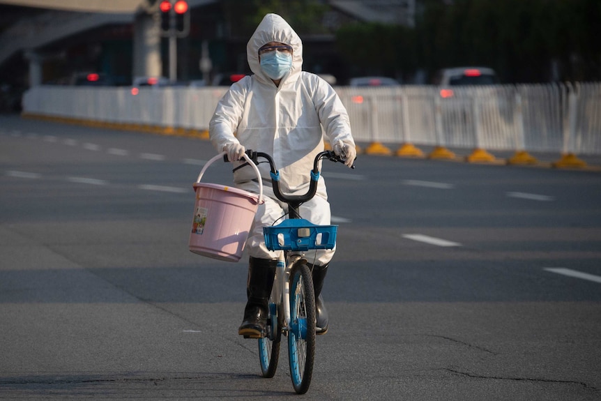 Un residente con máscara y demanda contra los ciclos del coronavirus en Wuhan.