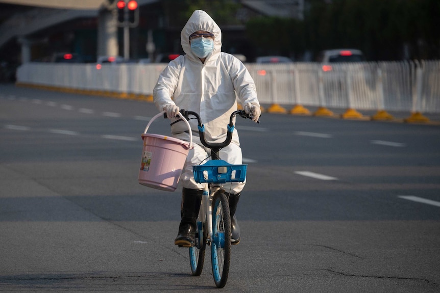 A resident wearing mask and suit against the coronavirus cycles in Wuhan.