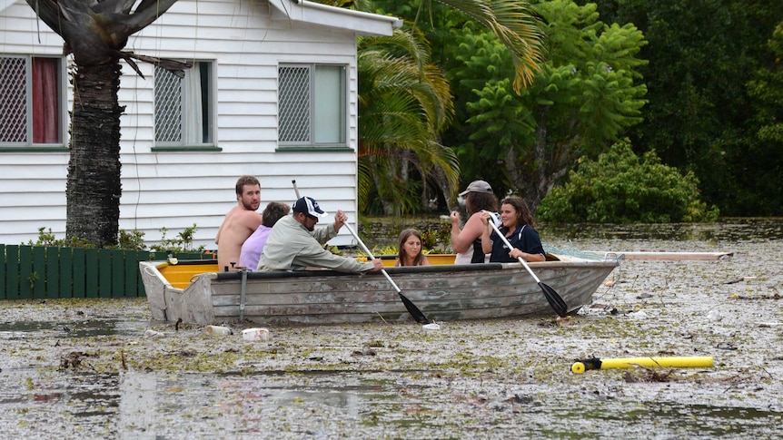 People in a boat negotiate floodwaters and debris in Bundaberg.