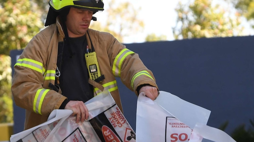 A firefighter is seen carrying a hazardous material bag into the South Korean consulate in Melbourne.