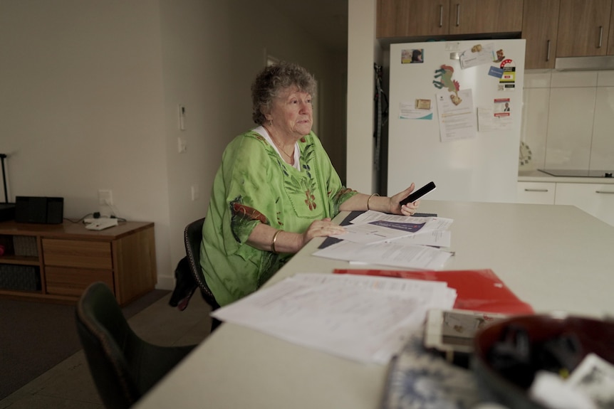 Karen Lancaster sits at her kitchen bench with papers strewn across the table.