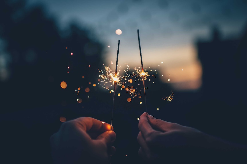 Two hands hold burning sparklers to depict a sexual spark between the couple.