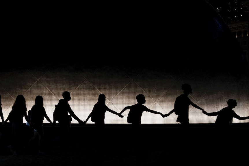 The silhouettes of masked protests, linking hands, against the HK skyline