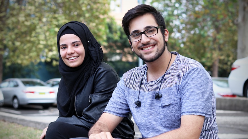 Sara Al Arnoos and Amro Zoabe sit together on a step smiling at the camera.
