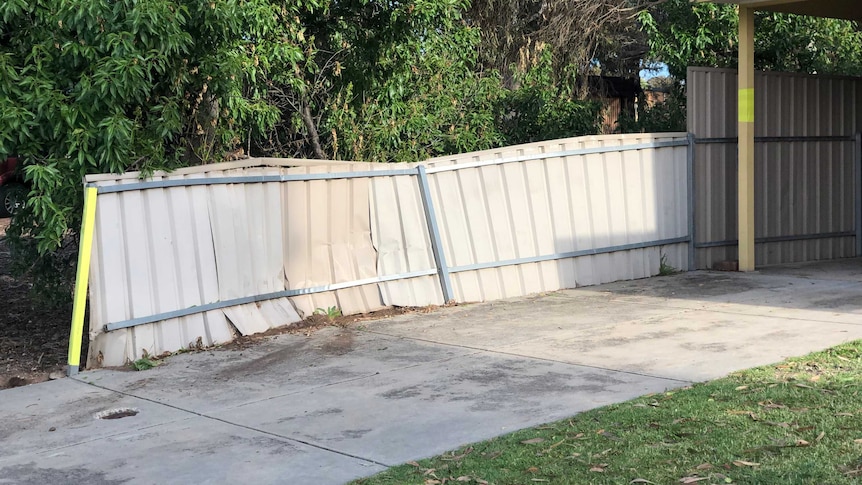 A damaged fence in the front yard of a house