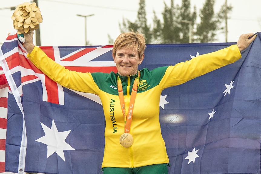 Paralympian gold medalist with her gold medal after winning a cycling race.