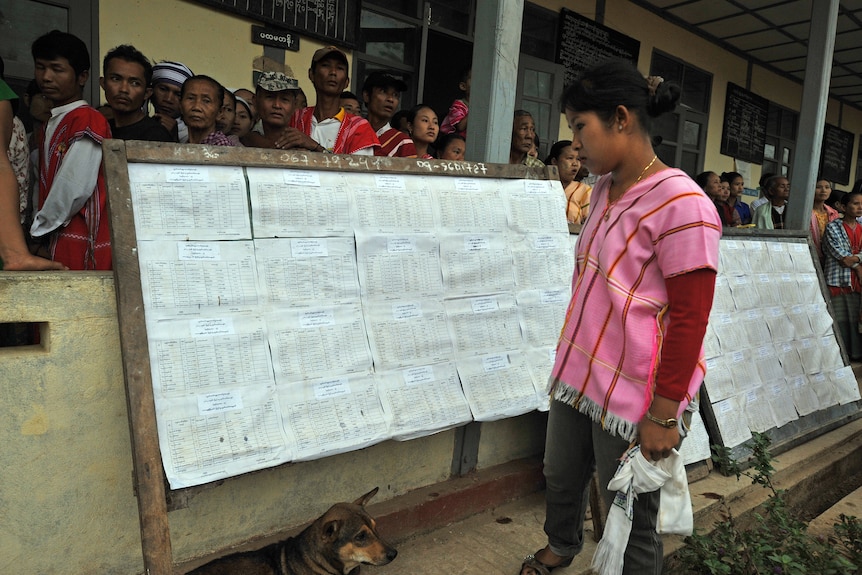A woman checks her name on the voters' list before voting at a polling station in Kawhmu, Burma.