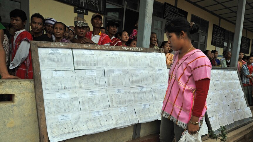 A woman checks her name on the voters' list before voting at a polling station in Kawhmu, Burma.