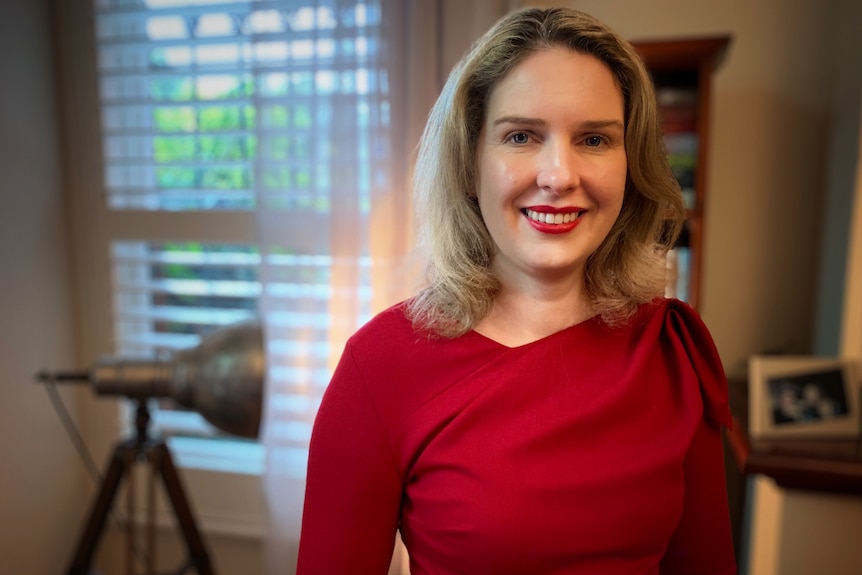 Woman in red smiles at camera. 