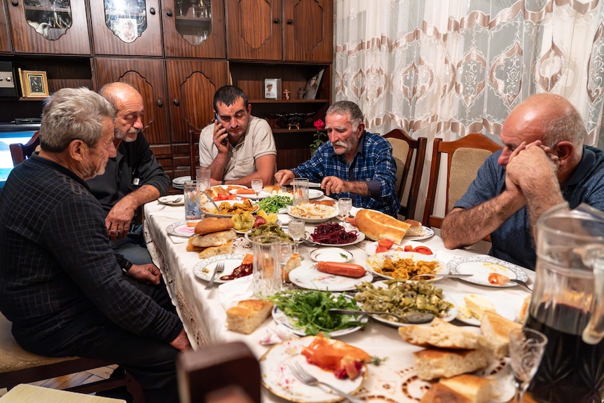 A group of people sit gathered around a table with heaping plates of food.
