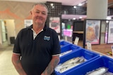 Man stands in front of a seafood store
