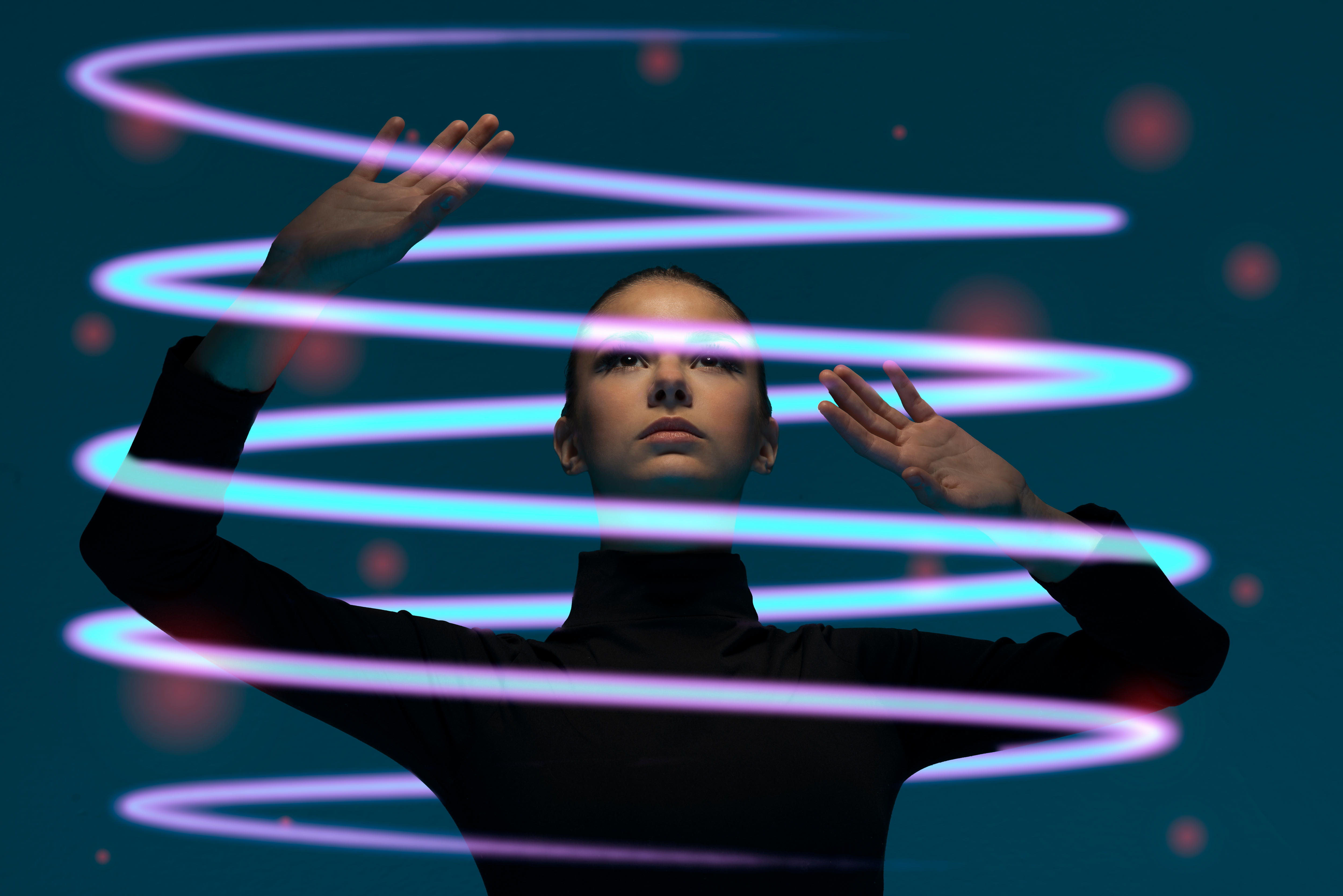 A woman stands inside a curling tube made of neon light