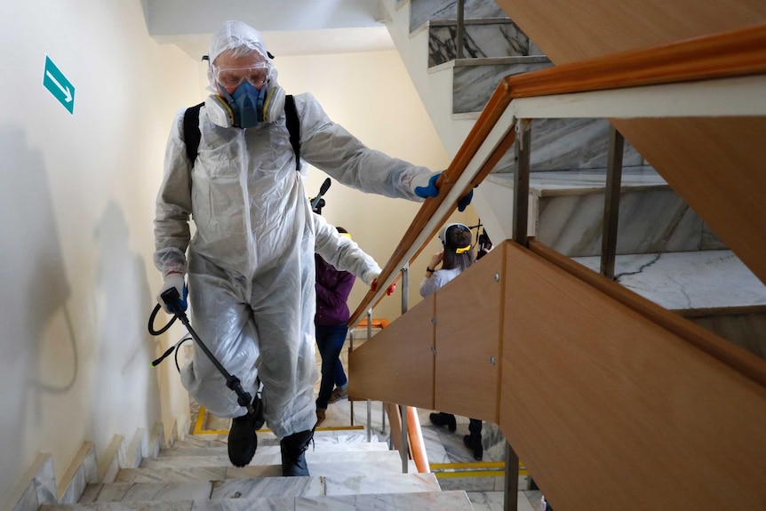 A man carries a sanitation hose up a flight of stairs.