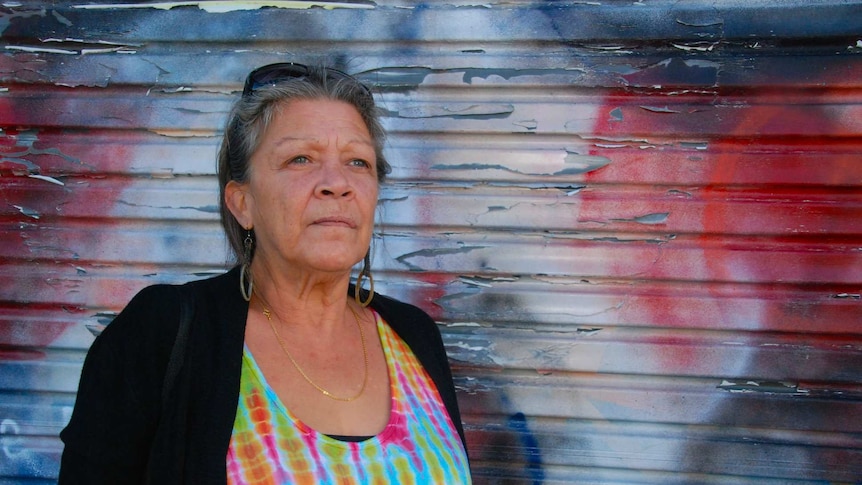 Older Indigenous woman against colourful background.