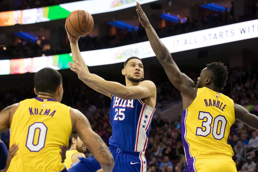 Ben Simmons shoots while being guarded by two LA Lakers players.