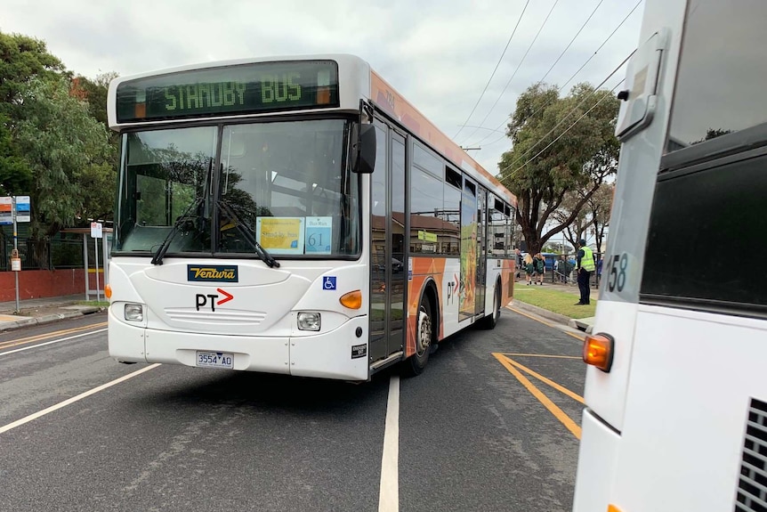 A bus replacing train services pulls out from a stop.