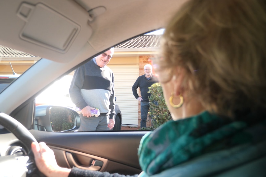 Woman talks to residents from the driver's seat