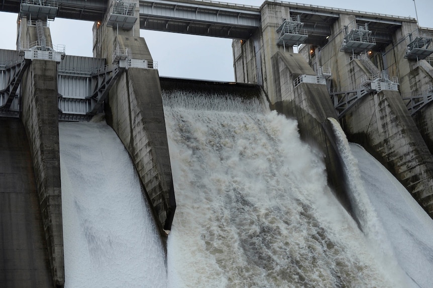 Water flows over the top of a dam.