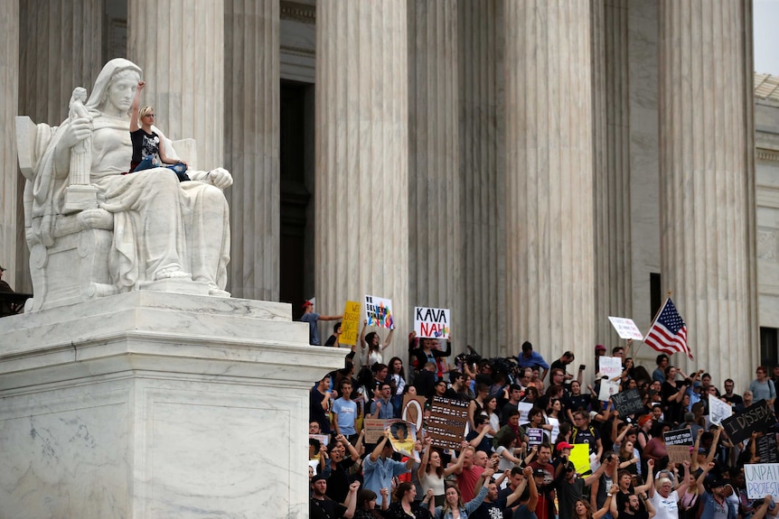 A protester sits in the lap of the Contemplation of Justice statue