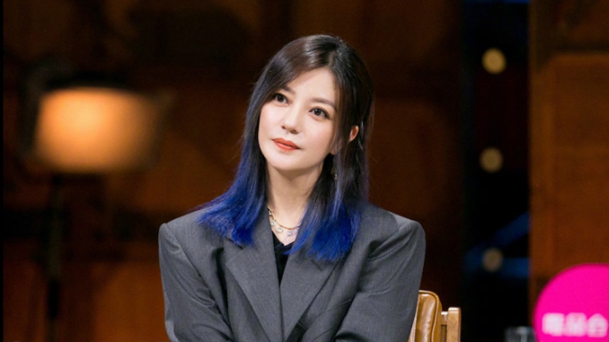 Billionaire actress Zhao Wei sits in a suit jacket and dyed blue hair in a file photo