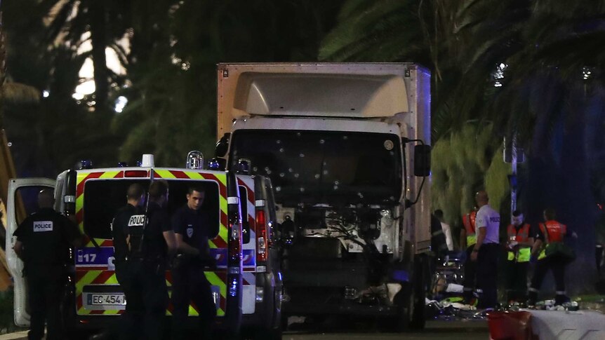 Police officers and rescued workers stand near a truck that ploughed into a crowd in Nice, France.