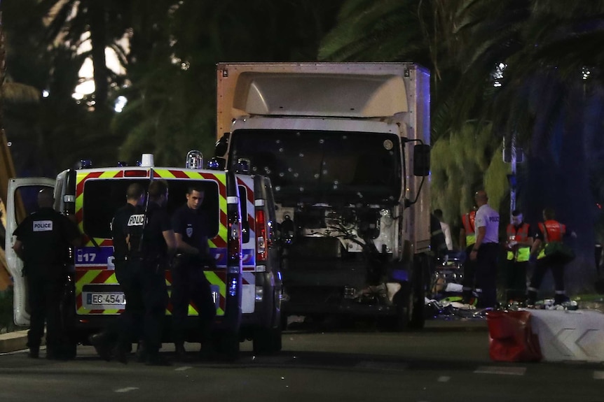 Police officers and rescued workers stand near a truck that ploughed into a crowd in Nice, France.
