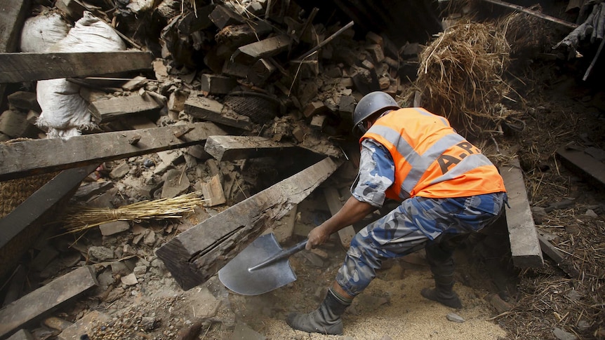 Rescue team member works to dig out the trapped body of a woman from a collapsed house a day after an earthquake in Bhaktapur, Nepal