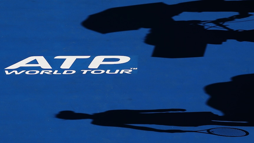Shadow on the ground of a tennis player, with the ATP World Tour printed on the court 