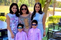 Three women and two boys smiling in an outdoor area of a restaurant