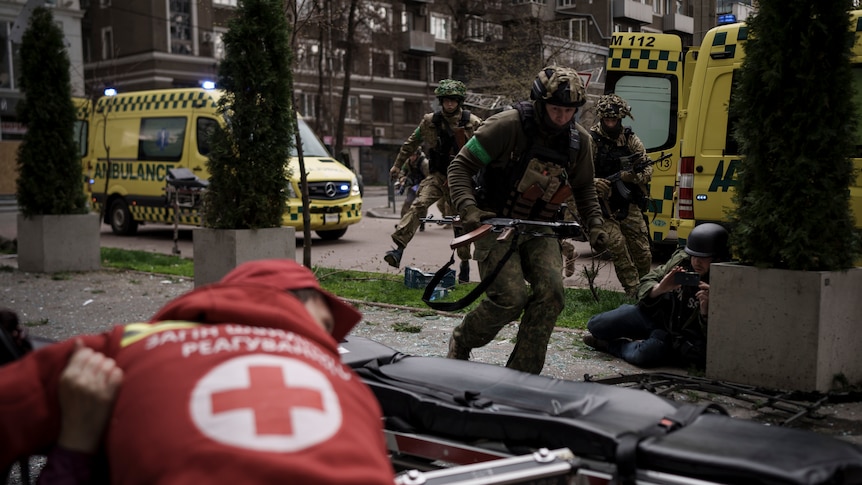 Ukrainian servicemen run for cover in front of ambulances