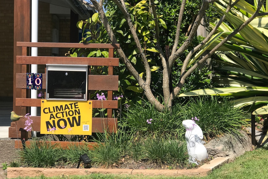 A letterbox with a yellow 'Climate action now' sign underneath it