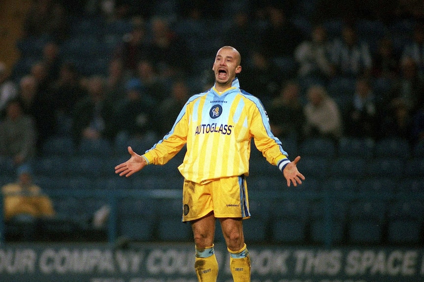 A man standing wearing a yellow soccer uniform with his arms held out