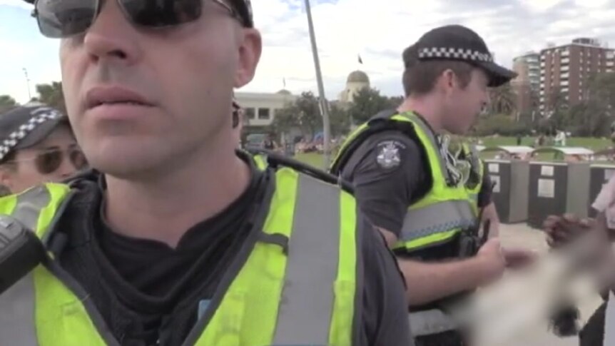 Police in high-visibility vests speak to people from both of the groups at the St Kilda foreshore.