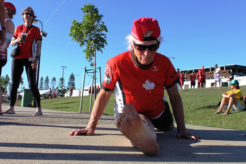 An 80-year-old woman from Canada does the splits on the ground.