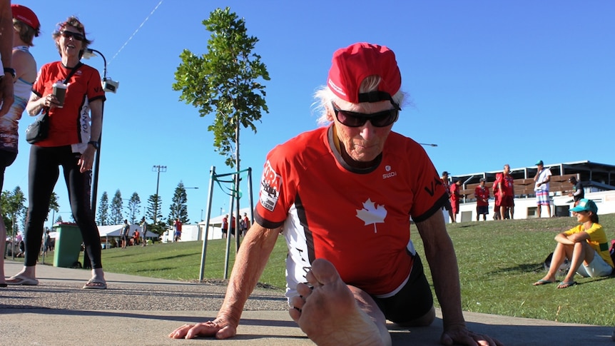 An 80-year-old woman from Canada does the splits on the ground.