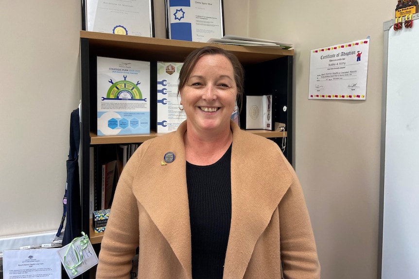 A woman smiling looking at camera, standing in office