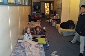 Children lie on mattresses in a hall way of a school.