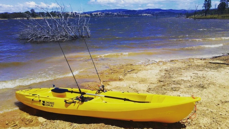 A yellow '2 Monks' kayak on a beach.