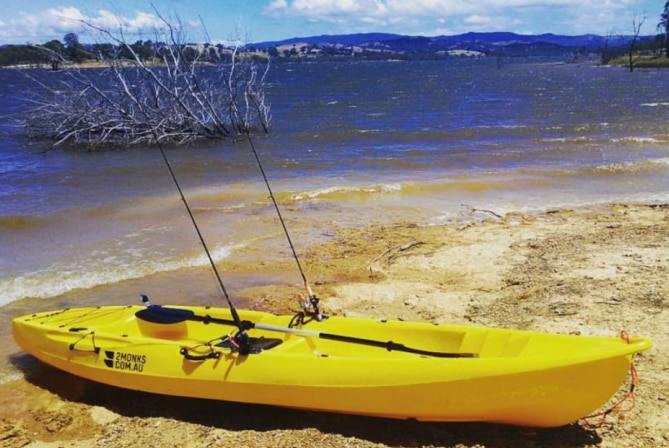 A yellow '2 Monks' kayak on a beach.
