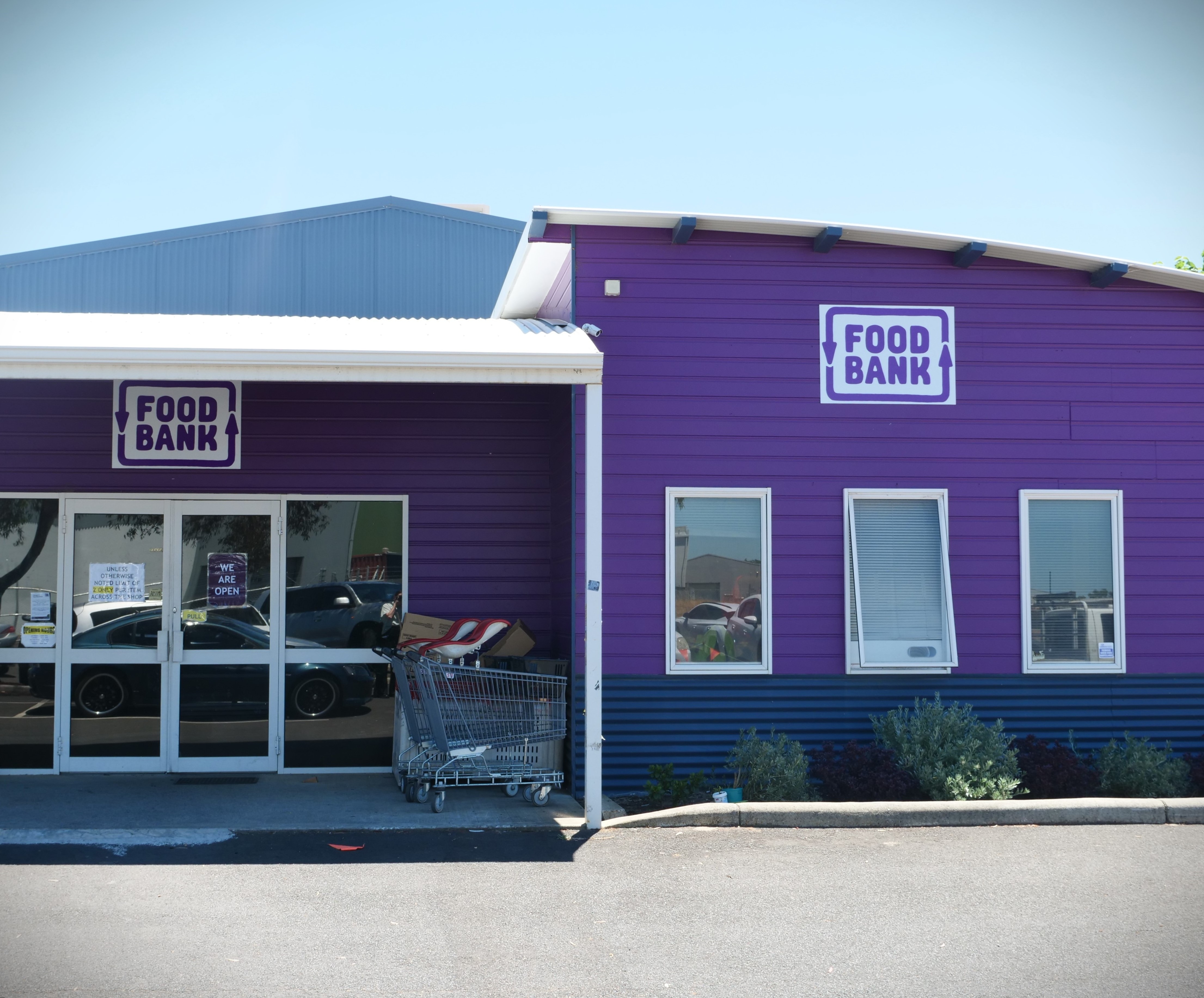 purplpe building with trolly infront of fron door against a blue sky. 