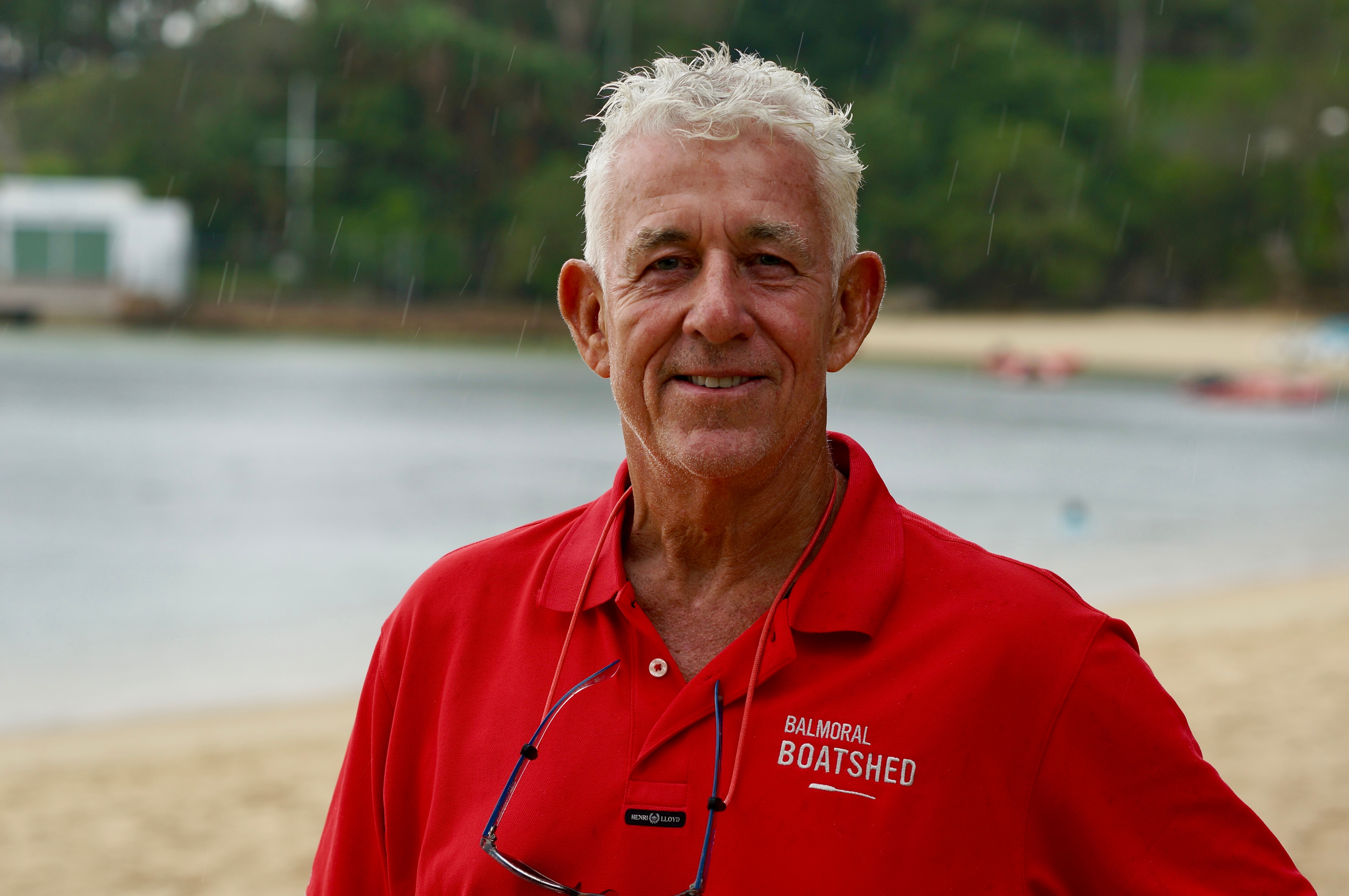 Steven Hedge tem cabelos grisalhos e uma camisa brilhante e posa para uma foto na praia.