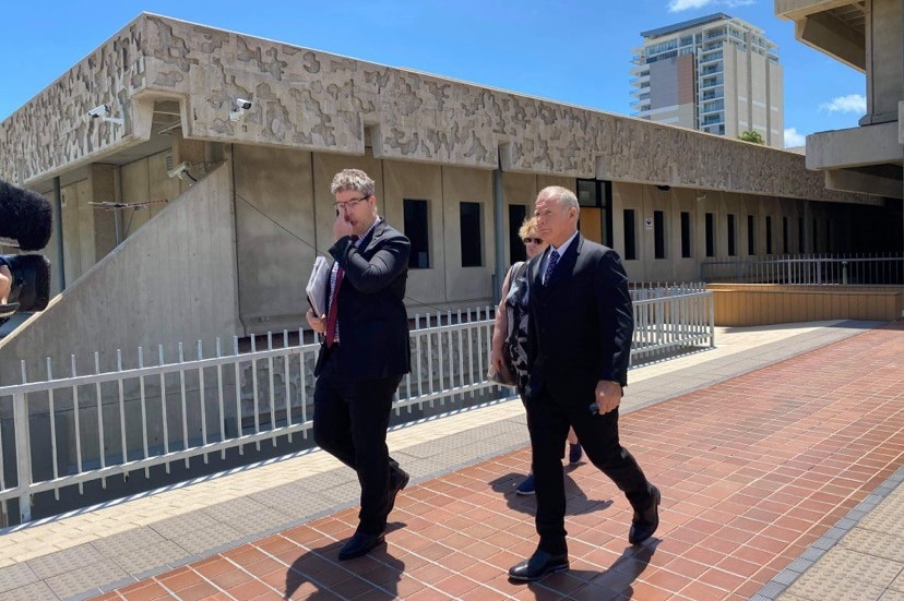 two men in black suits walking outside of Townsville Magistrates Court