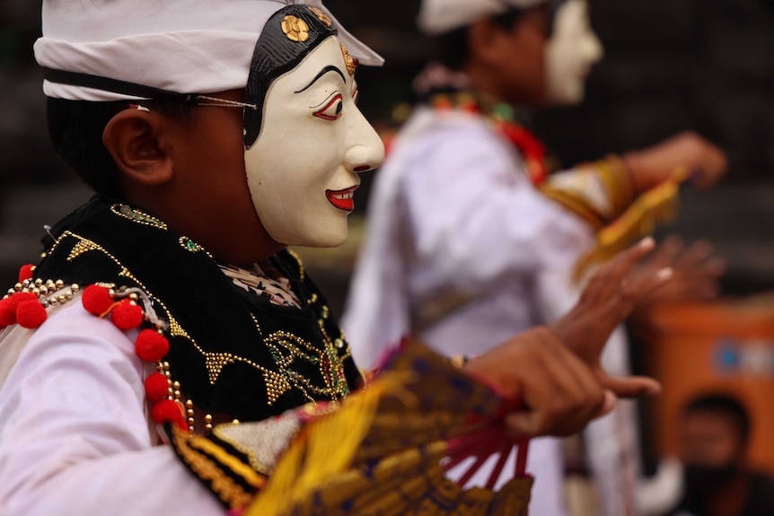 A dancer wears a traditional mask.