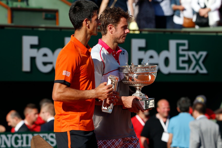 Novak Djokovic holds the French Open runner-up trophy and Stan Wawrinka the winner's in 2015.