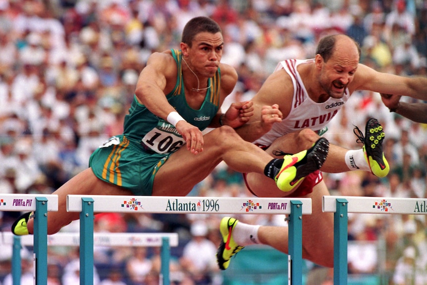 Two men competing in a hurdling event at track and field competition